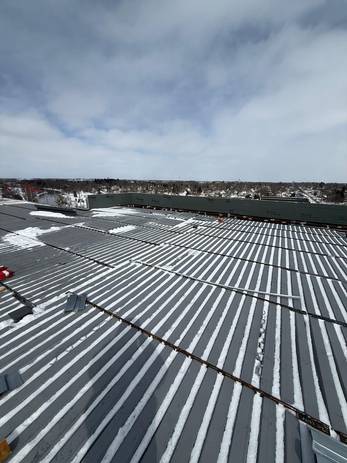 Snow-dusted steel roof deck across a large commercial roof