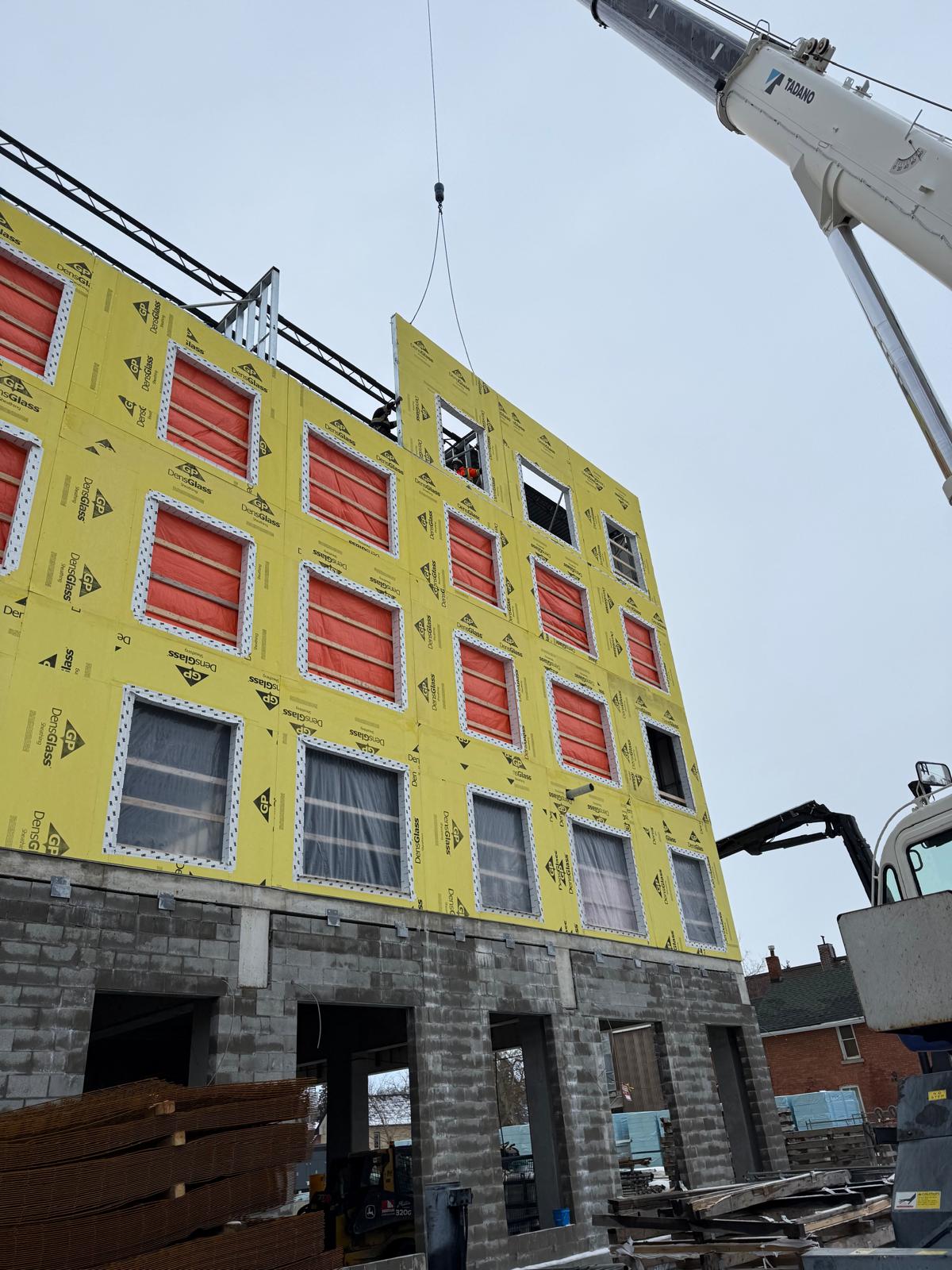Crane lifting a prefabricated sheathed wall panel into place