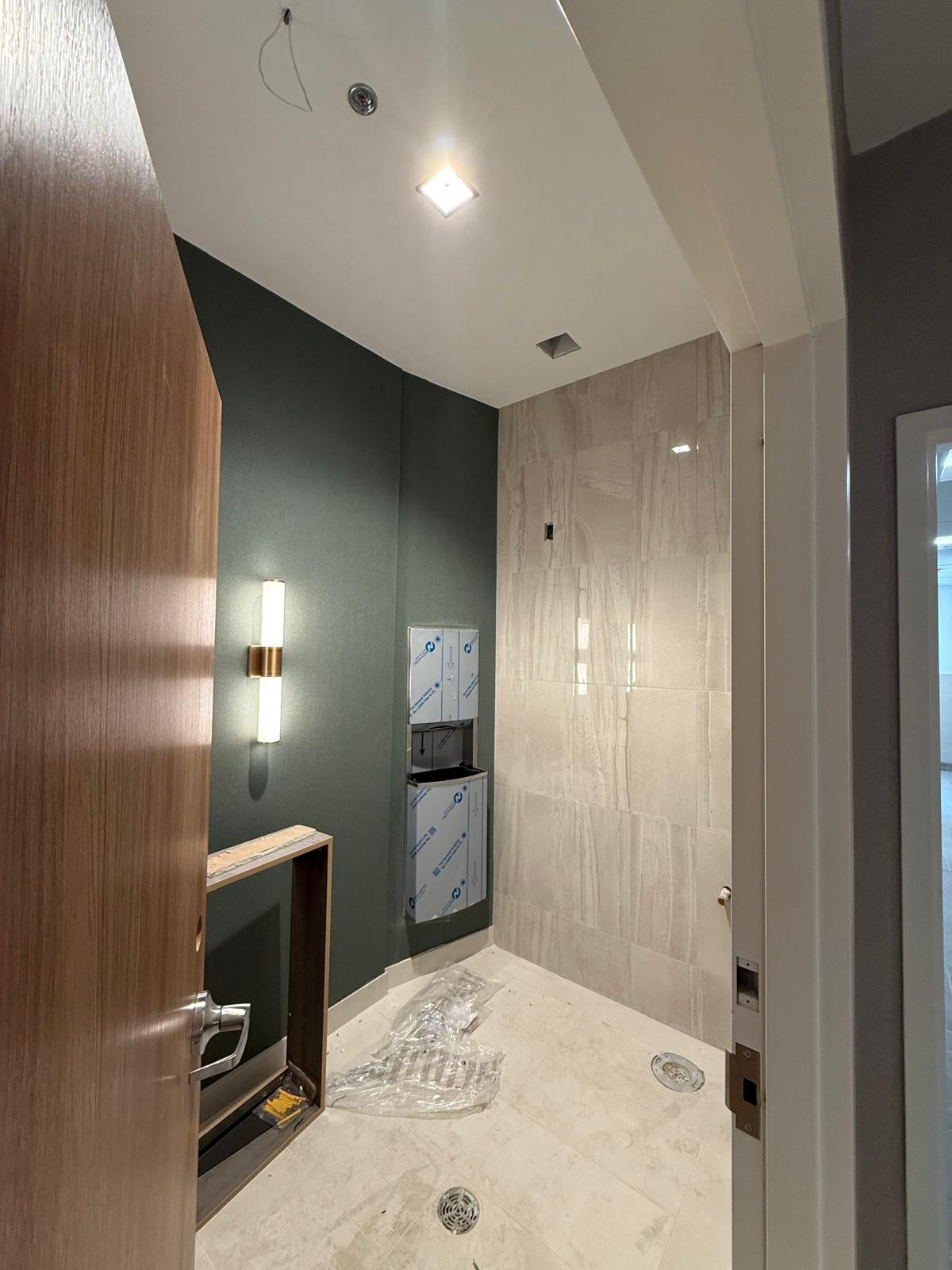 Commercial washroom with large-format wall tile, painted feature wall and millwork installation