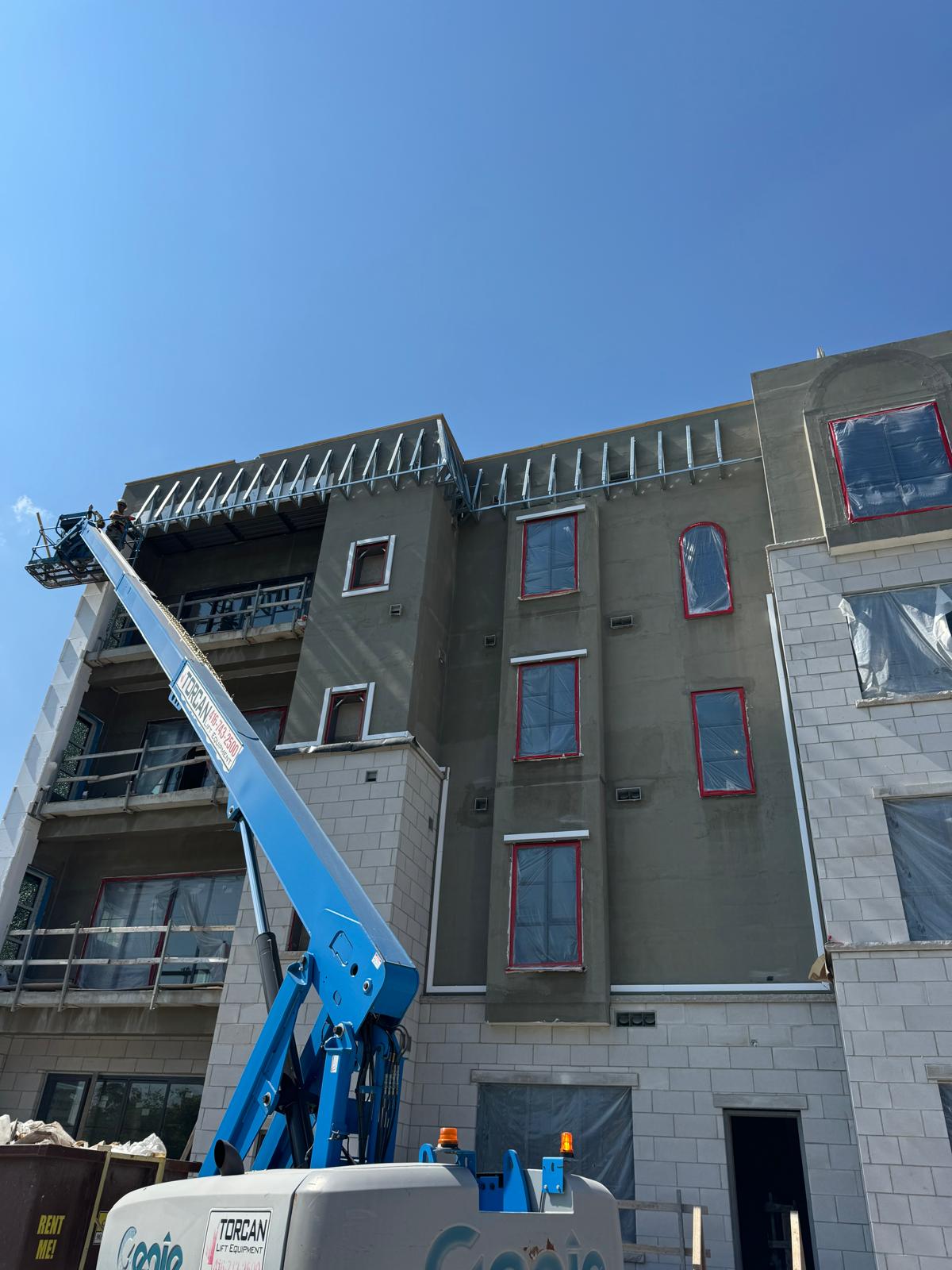 Boom lift crew installing roof framing on a four-storey building