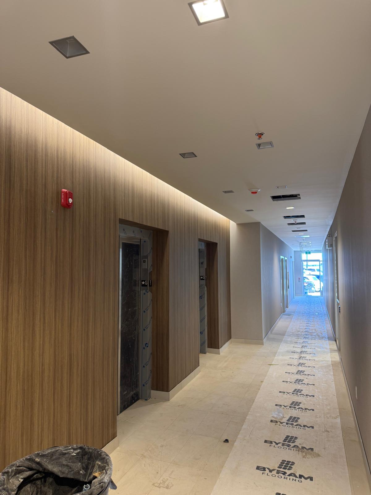 Finished commercial corridor with wood wall panels, recessed lighting and tiled floor