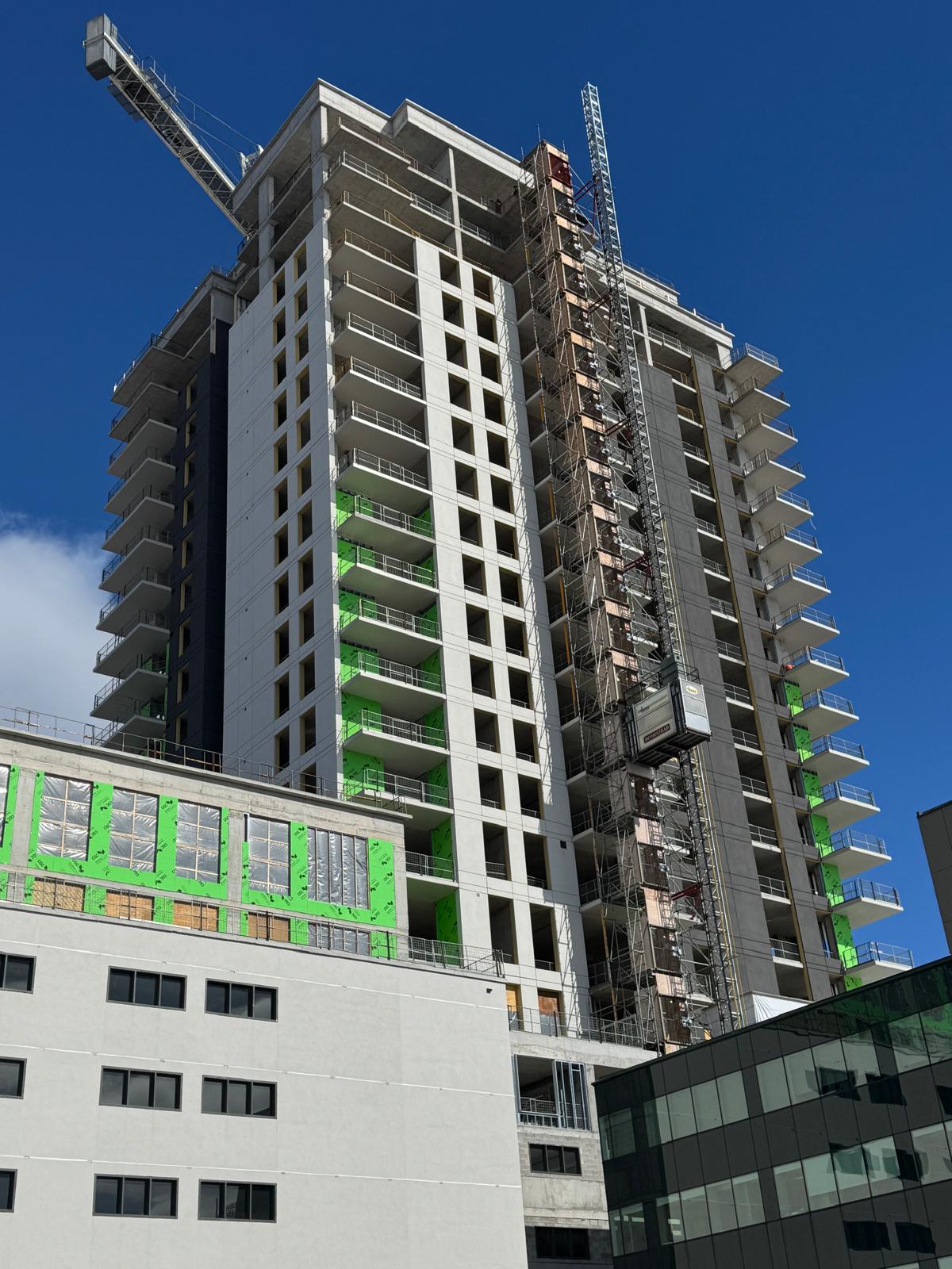 Concrete high-rise under construction with hoist and balcony slabs