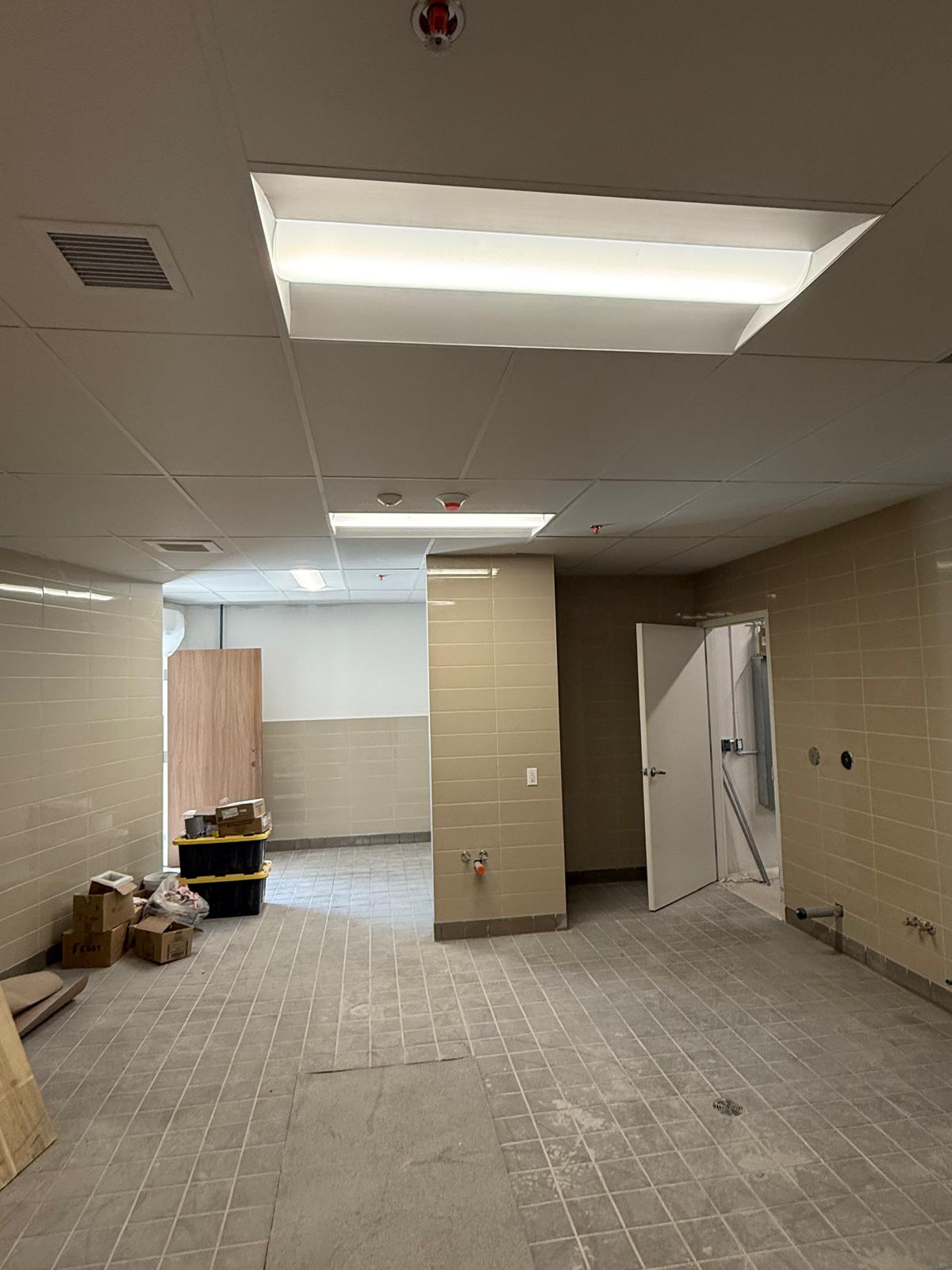 Tiled commercial washroom with suspended acoustic ceiling and integrated lighting