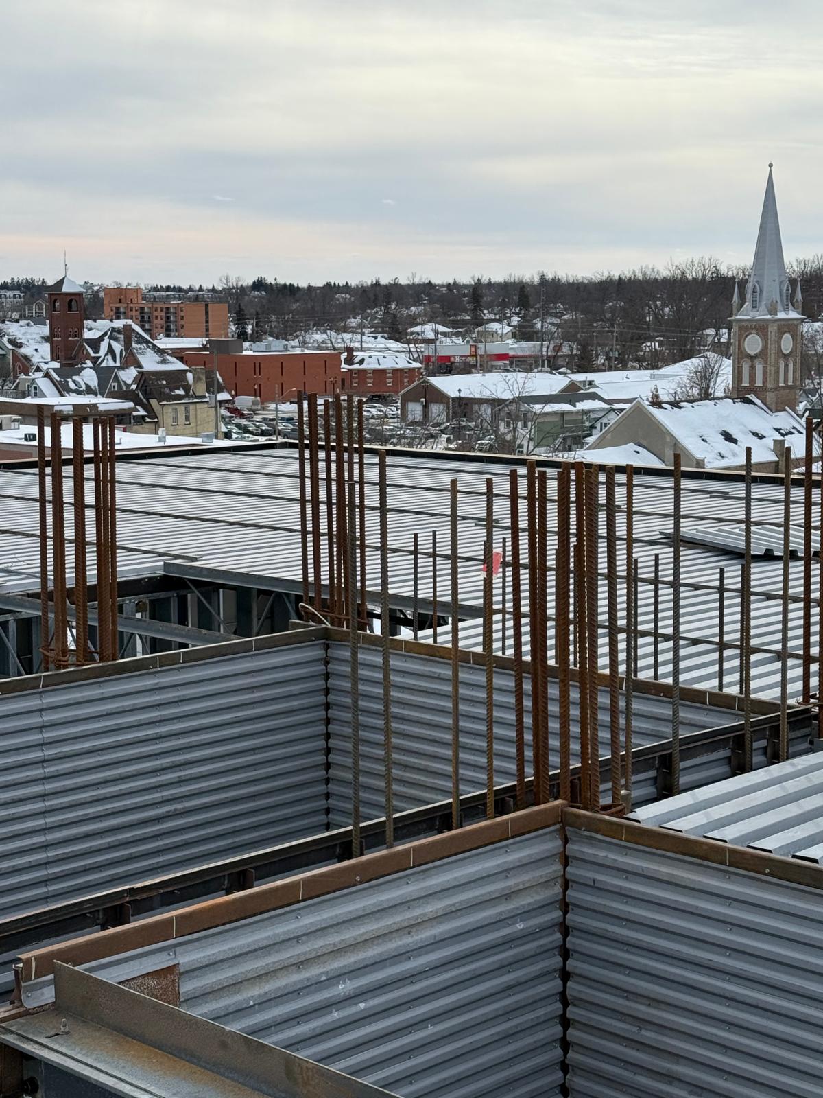 Steel decking and rebar columns overlooking a snow-covered town