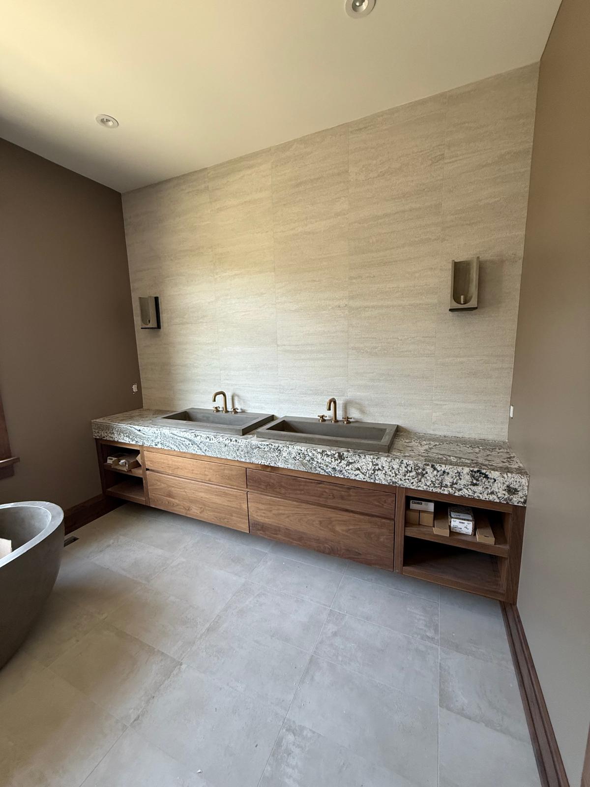 Custom double vanity with stone counter, wood cabinetry and large-format wall tile