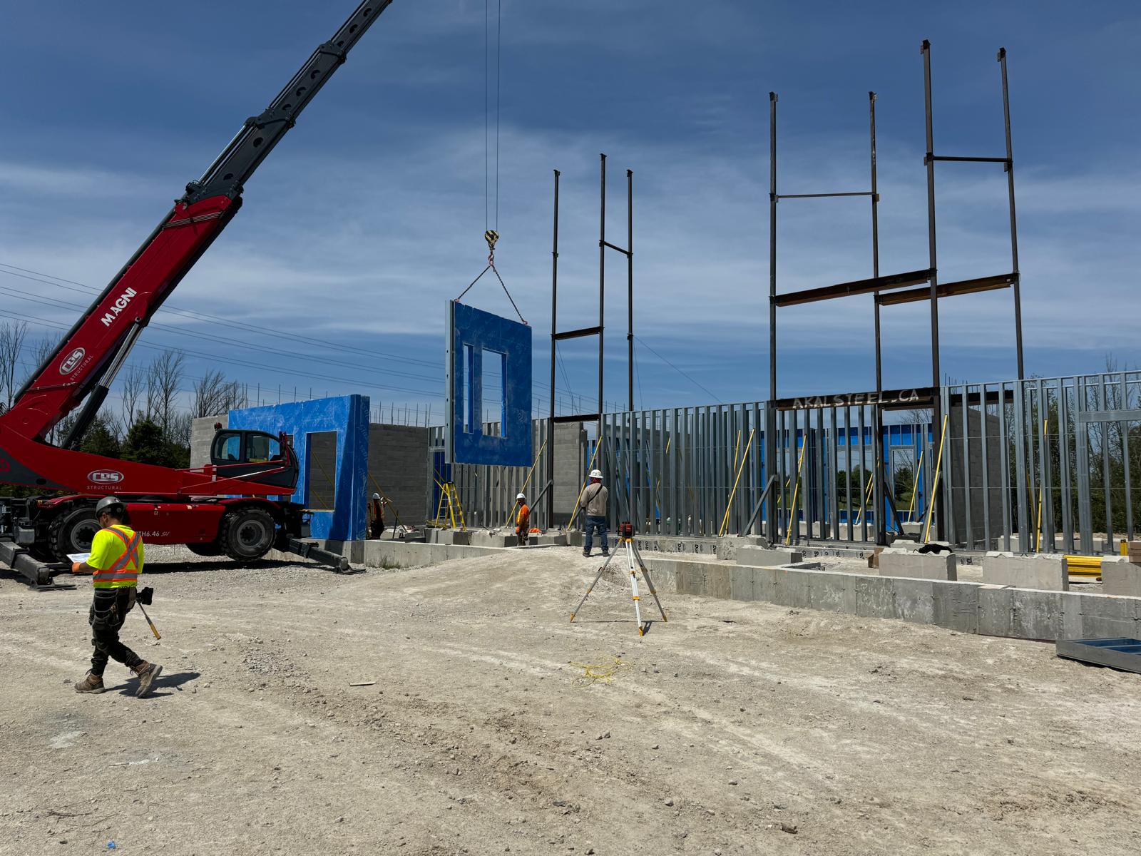 Crane setting a prefabricated wall panel within a structural steel commercial frame