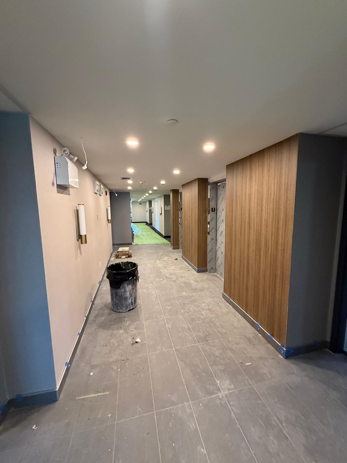Commercial corridor with wood wall panels, recessed lighting and tiled flooring nearing completion