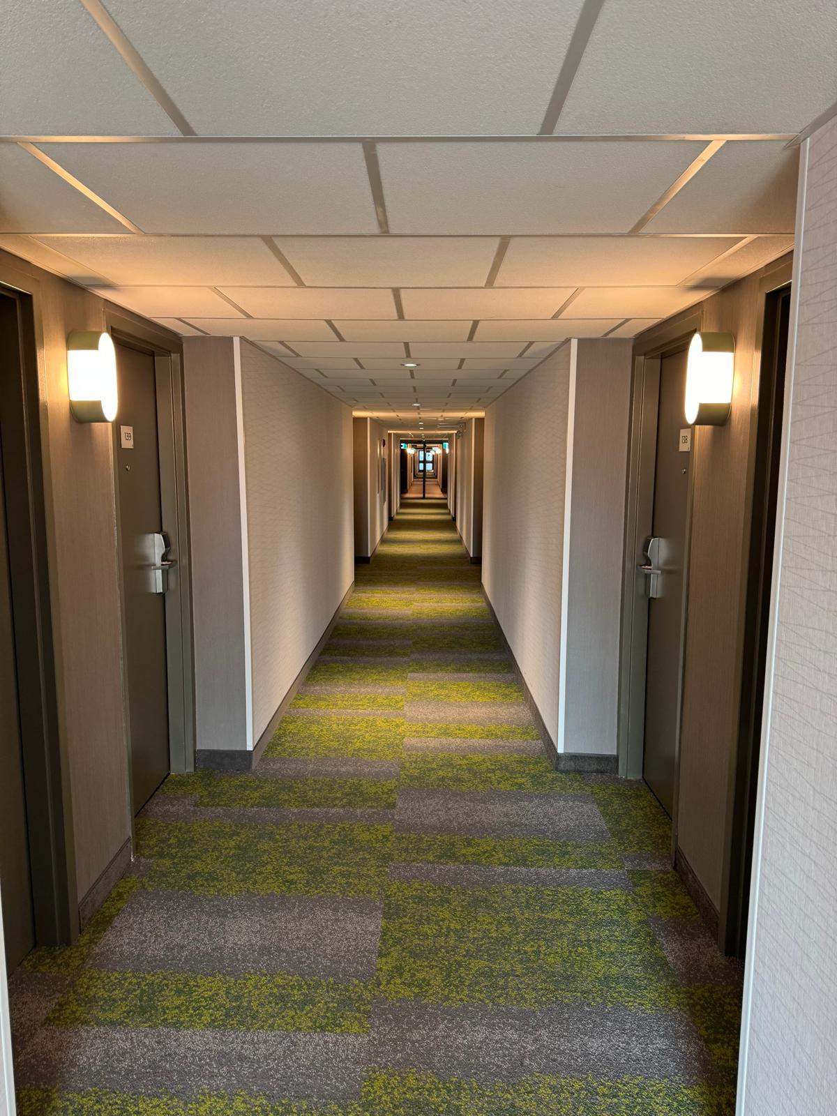Long completed hospitality corridor with acoustic ceiling and finished wall surfaces